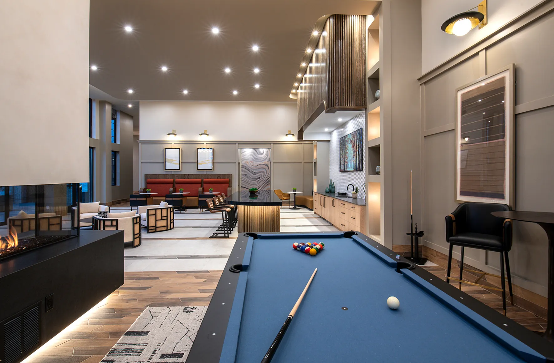 Luxurious modern lounge with elegant pool table, cozy fireplace, and stylish seating area in a spacious open-concept design.