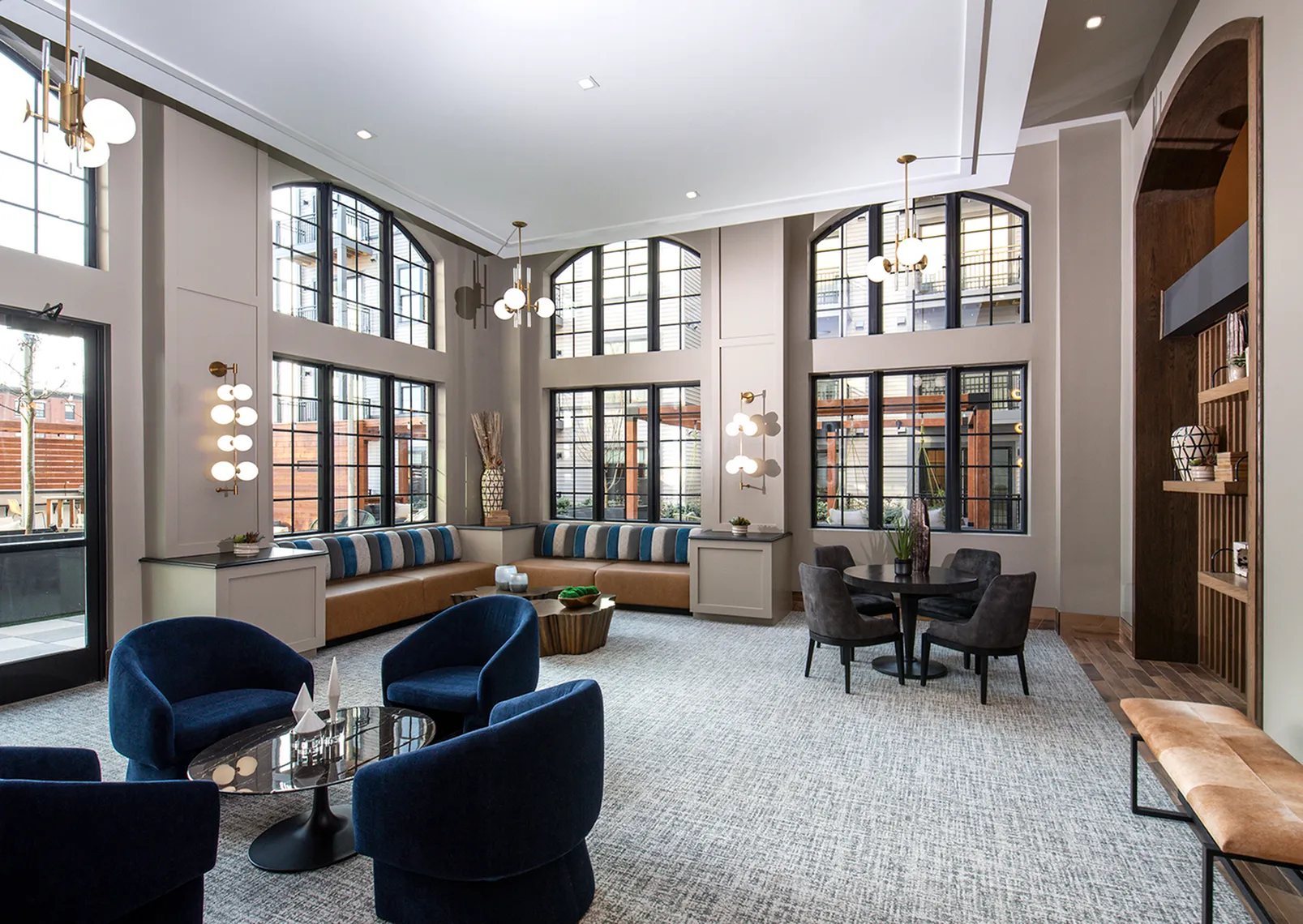 Elegant lounge area with tall windows, plush blue chairs, and modern lighting, perfect for relaxation and socializing.