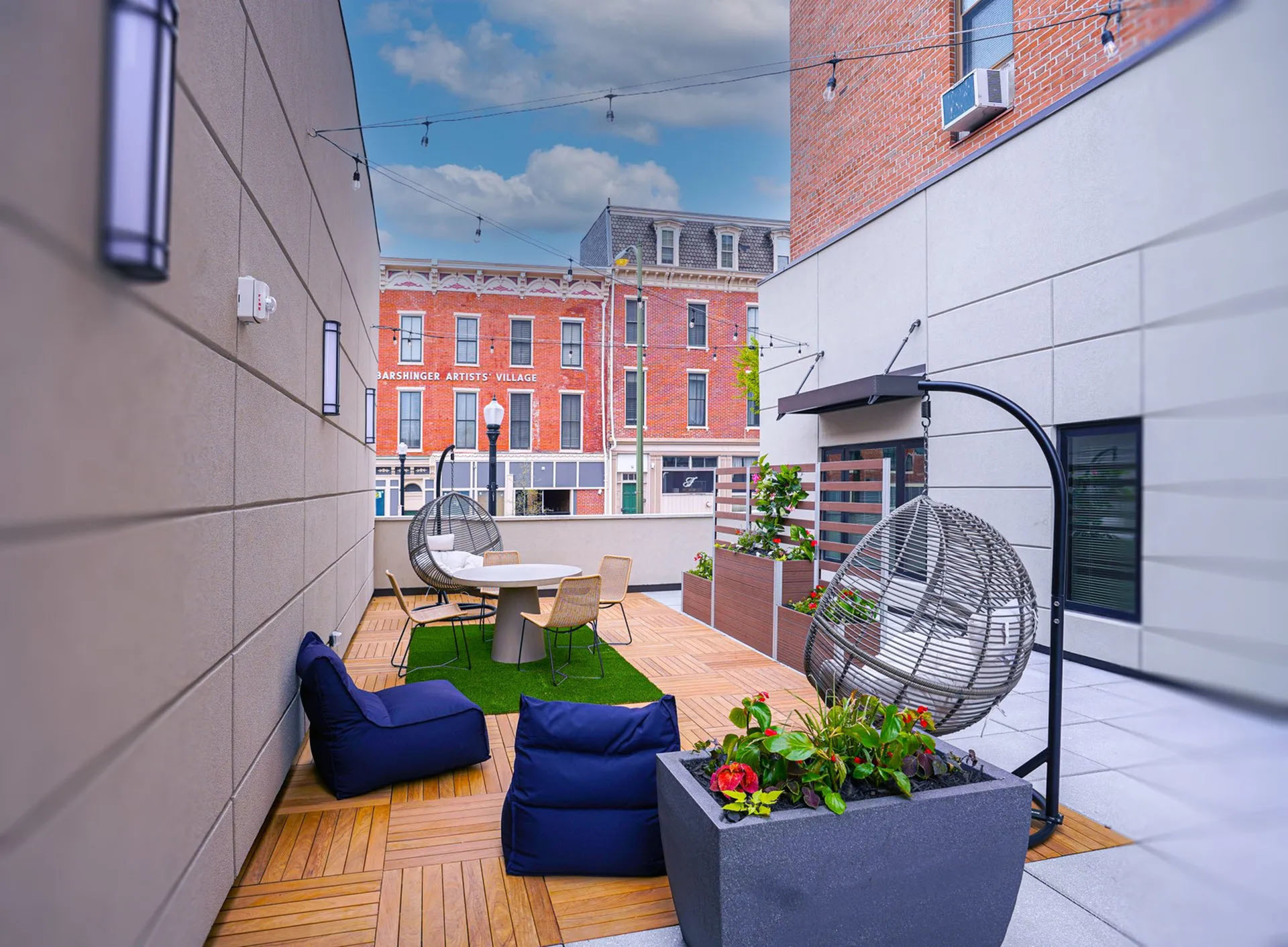 Charming urban rooftop patio with cozy seating, vibrant plants, and stylish hanging chairs, offering a perfect blend of relaxation and city views.