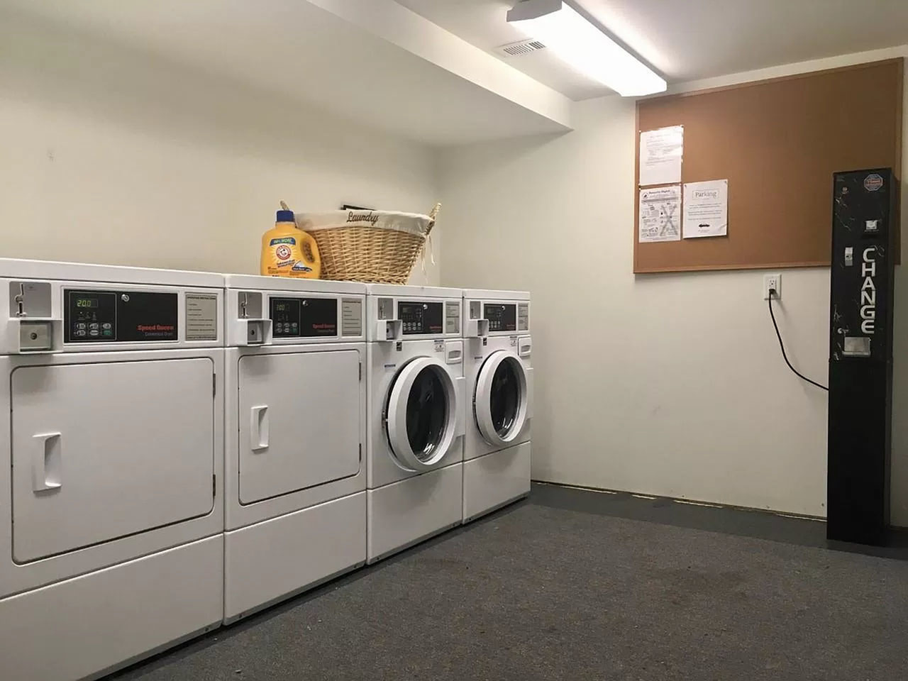 Modern laundry room featuring efficient washing and drying machines, detergent, and a convenient change machine, offering a clean and organized space.
