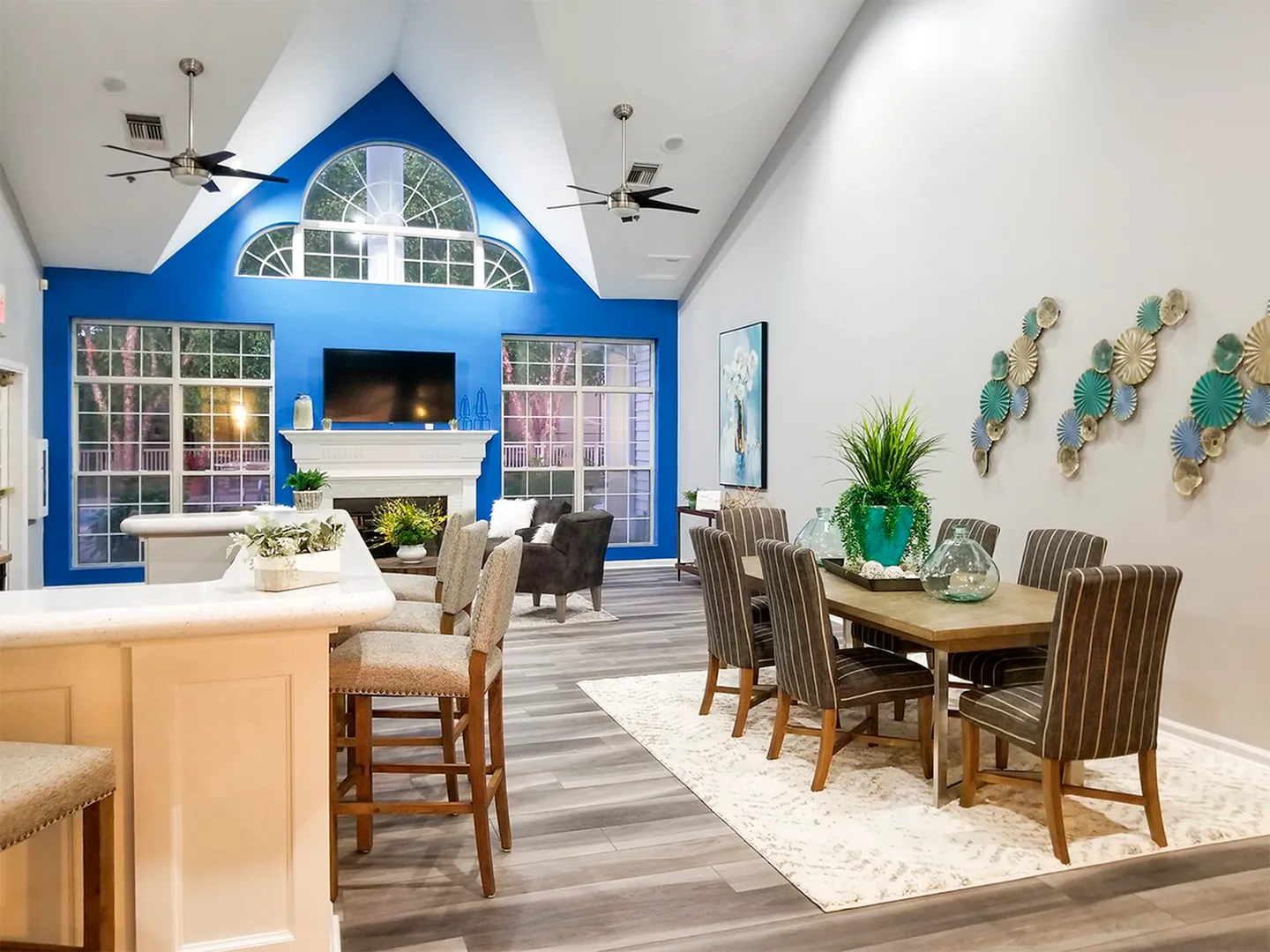 Elegant communal area with vaulted ceilings, cozy seating, and stylish dining space, highlighted by vibrant blue accent wall and modern decor.