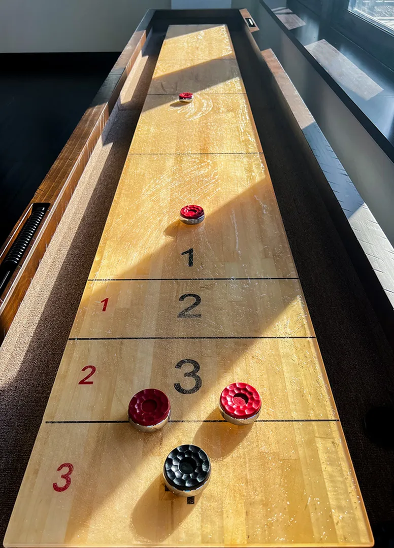 Bright and inviting shuffleboard table in a sunlit room, perfect for entertainment and leisure.