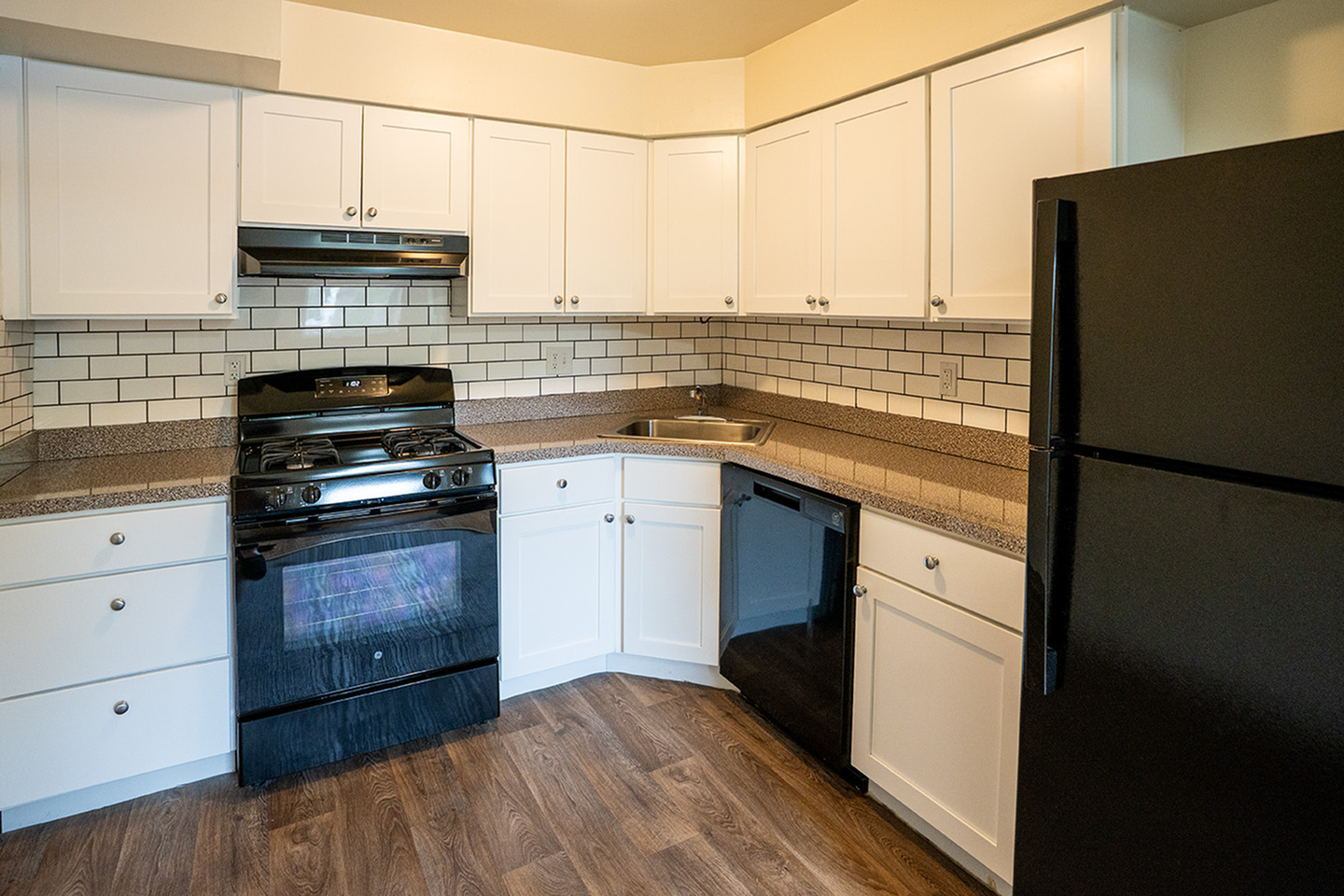 Modern kitchen boasts sleek black appliances, elegant white cabinetry, and stylish subway tile backsplash.