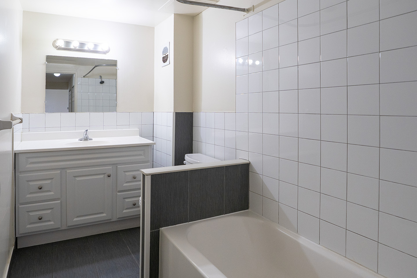 Sleek bathroom design featuring a modern vanity with ample storage, elegant lighting, and a clean tiled bathtub.