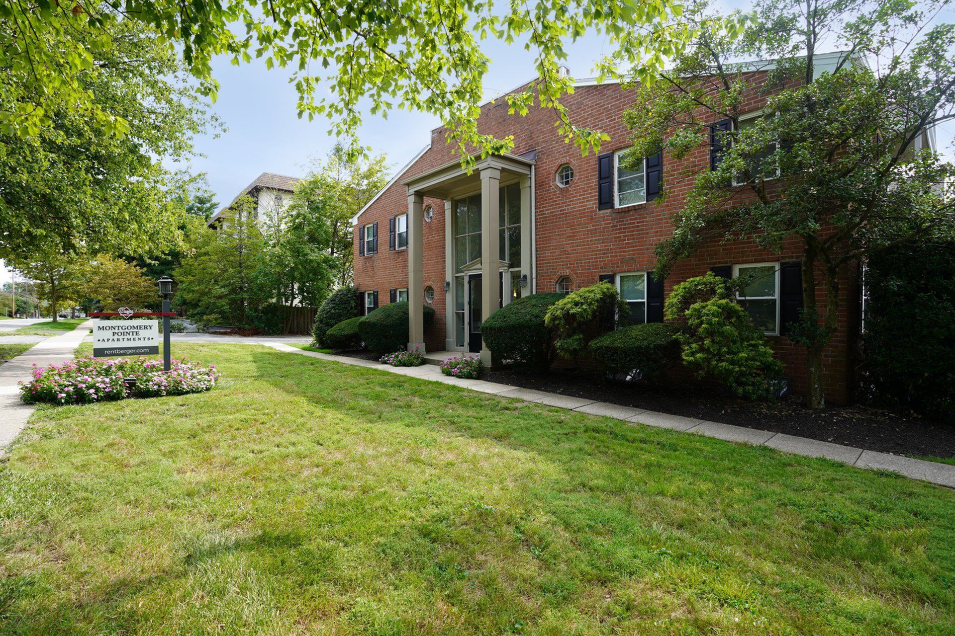 Charming Montgomery Pointe Apartments exterior showcasing classic brick architecture, lush green landscaping, and welcoming entrance.