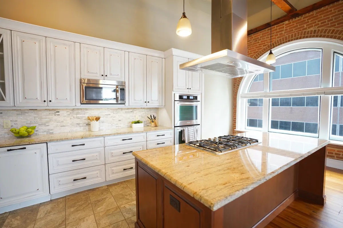 Elegant kitchen featuring modern stainless steel appliances, a large central island, and bright arched windows for natural light.