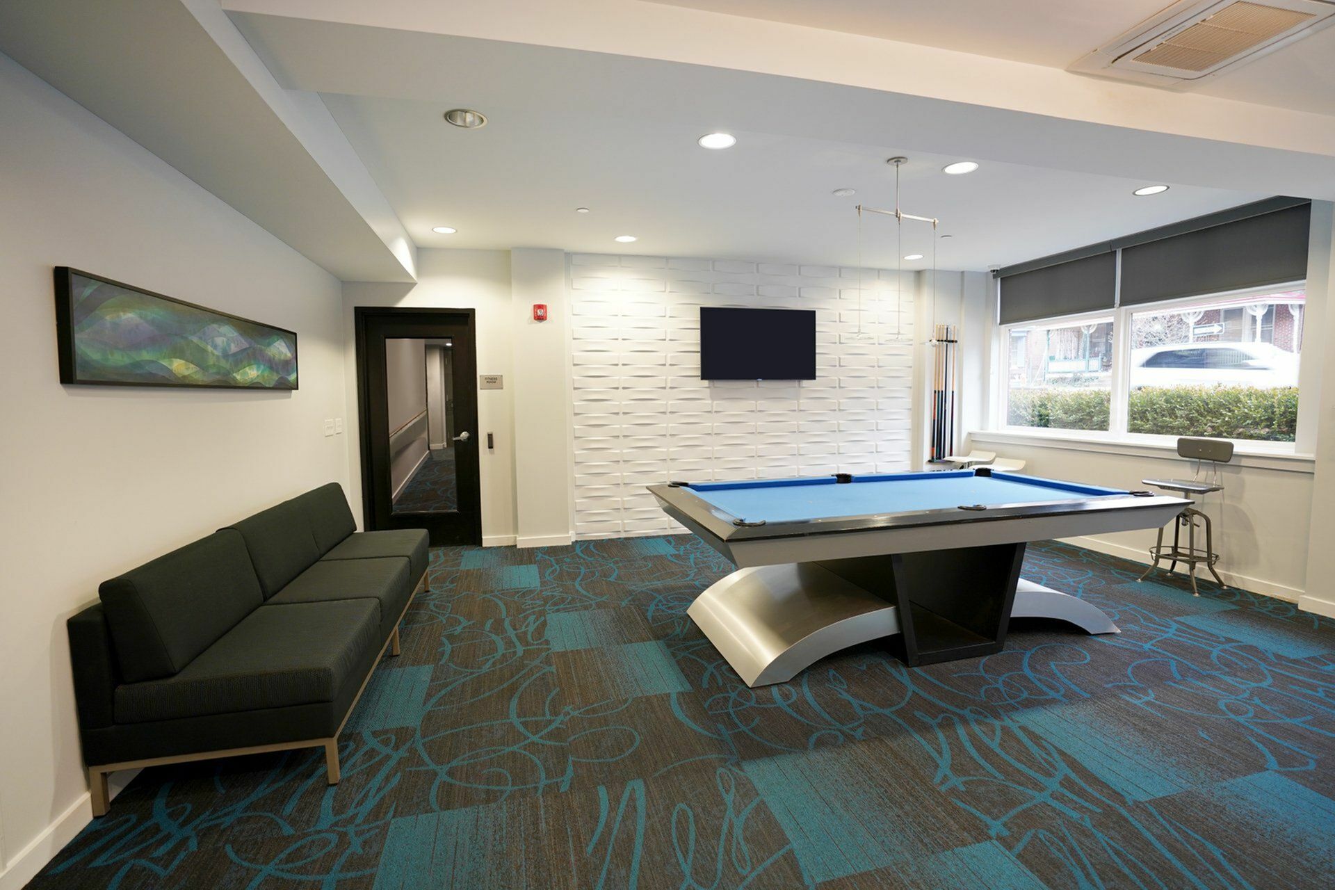 Elegant game room with pool table, modern seating, and bright natural light through large windows.