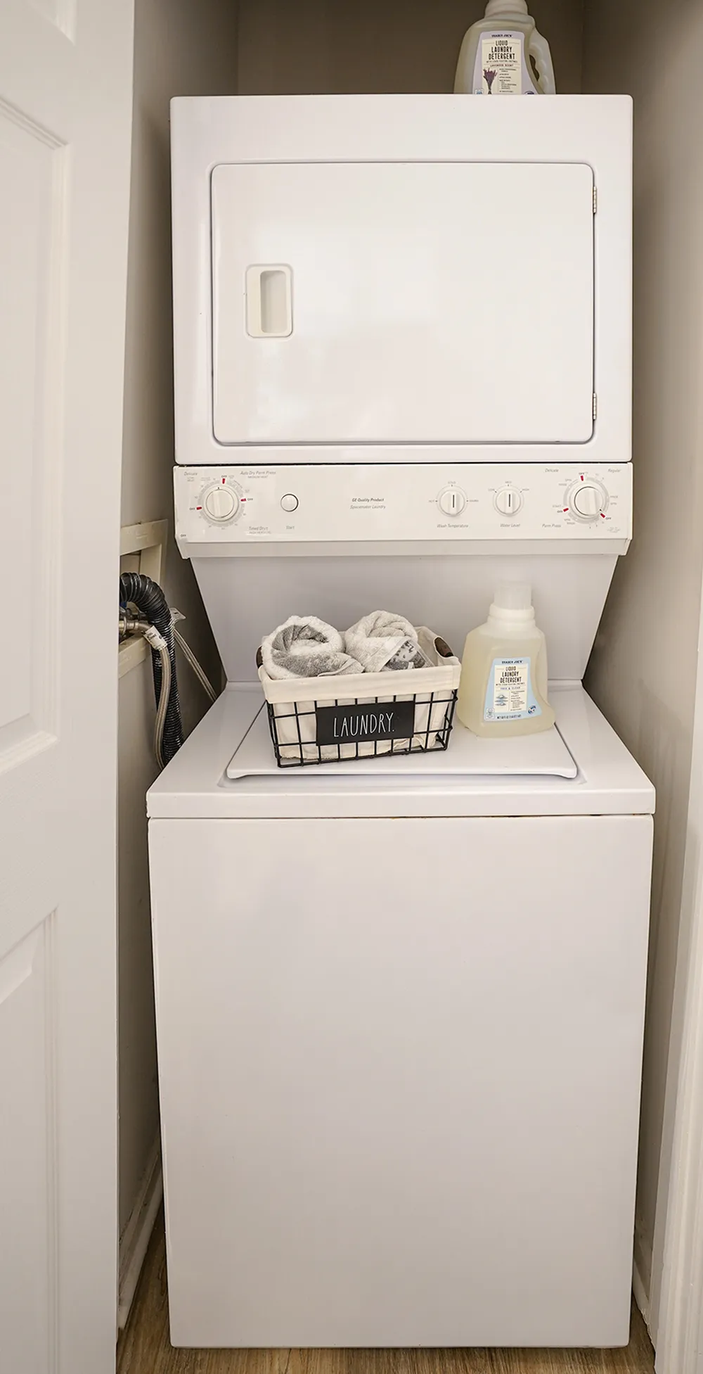 Compact and efficient laundry area with modern stackable washer and dryer, featuring practical storage for laundry essentials.