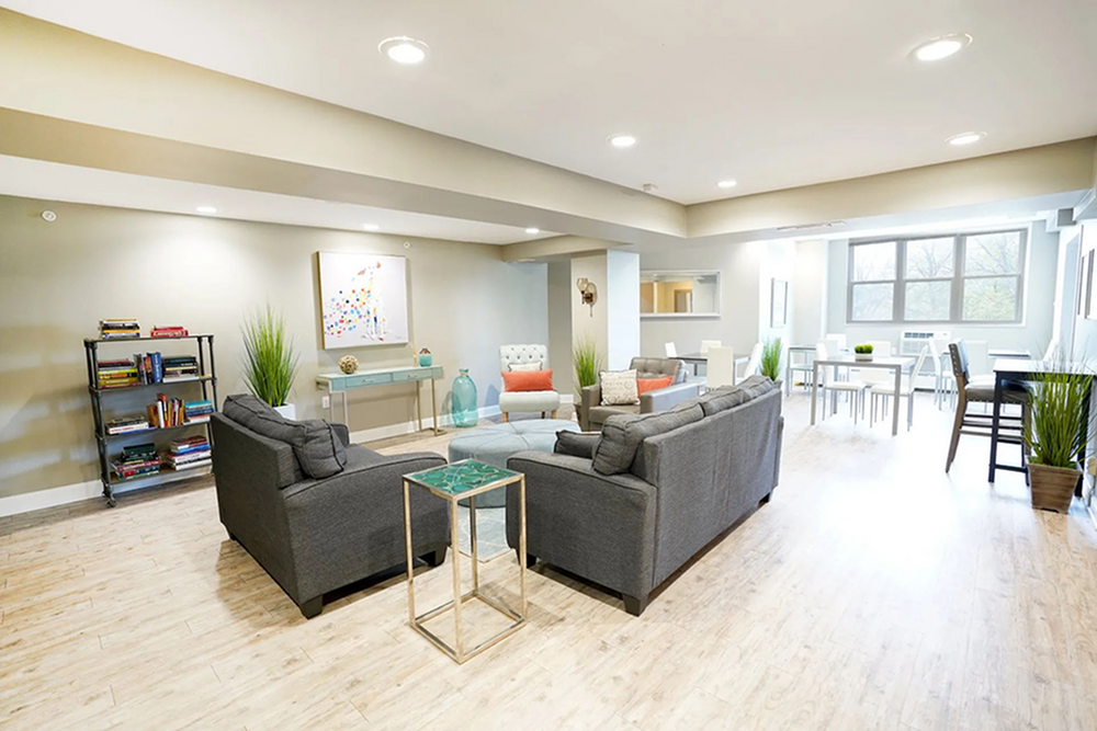 Bright and modern open-plan living space with cozy grey sofas, stylish decor, and ample natural light from large windows, perfect for relaxation and entertaining.