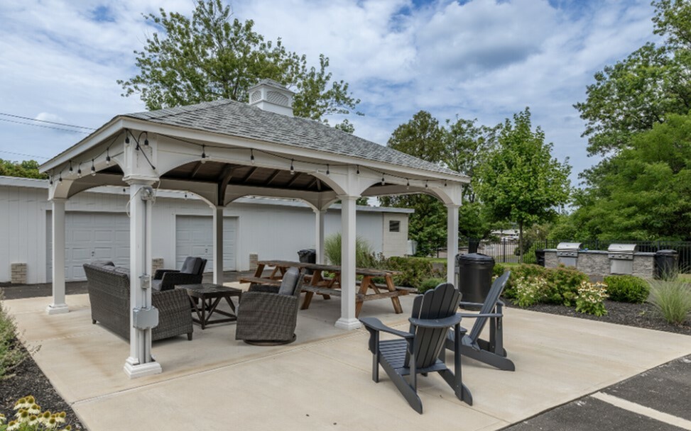 Inviting outdoor gazebo with cozy seating, ideal for relaxation and social gatherings, surrounded by lush greenery and clear skies.