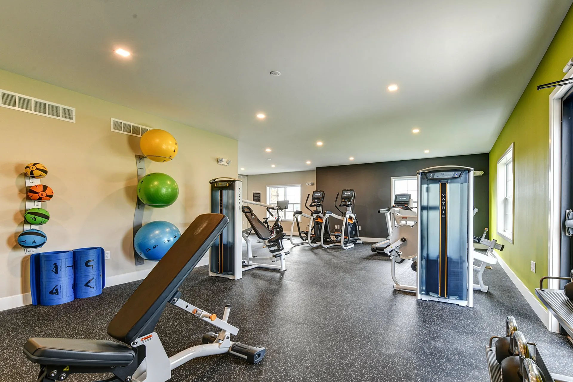 Modern fitness center featuring top-notch gym equipment, bright windows, and vibrant color accents for an energizing workout experience.