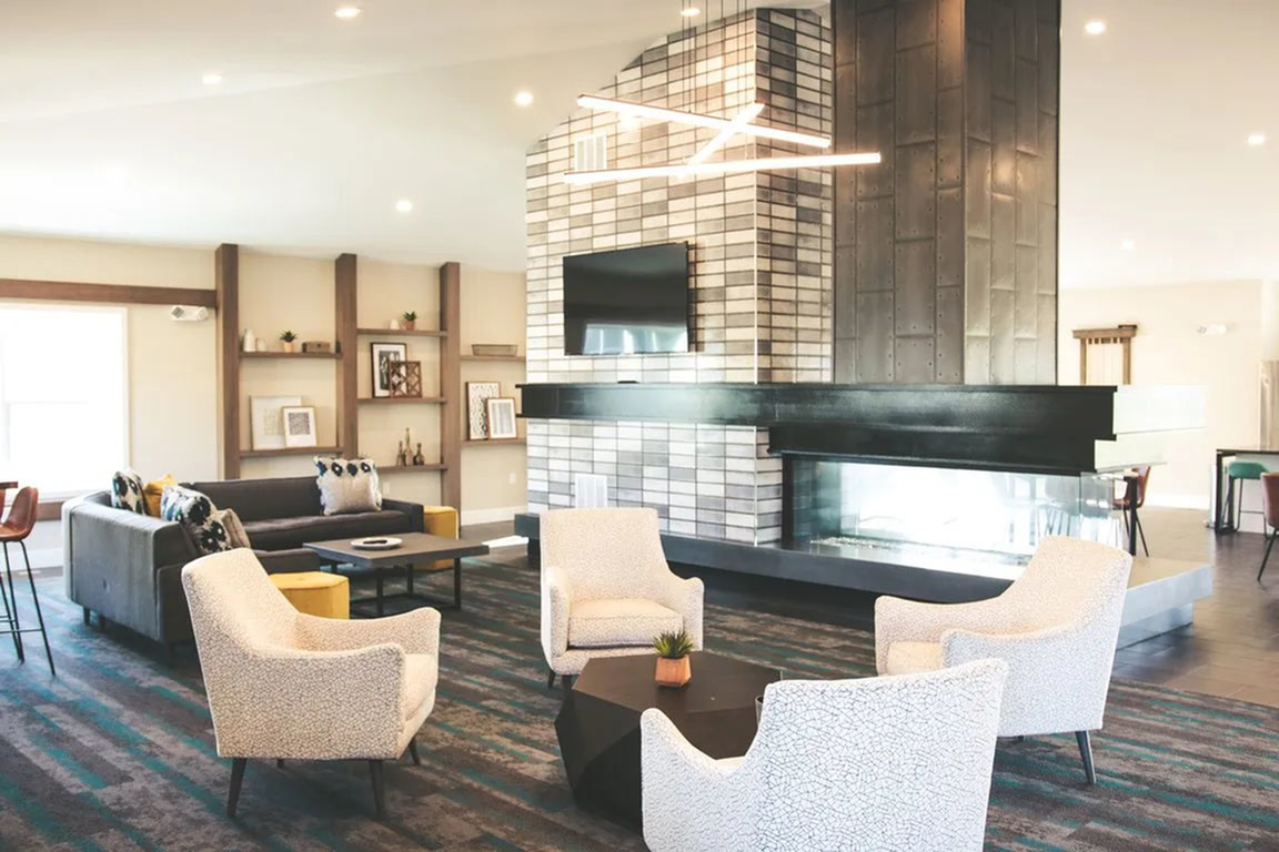 Contemporary lounge area featuring cozy armchairs, a modern fireplace, sleek shelving, and stylish decor accents.
