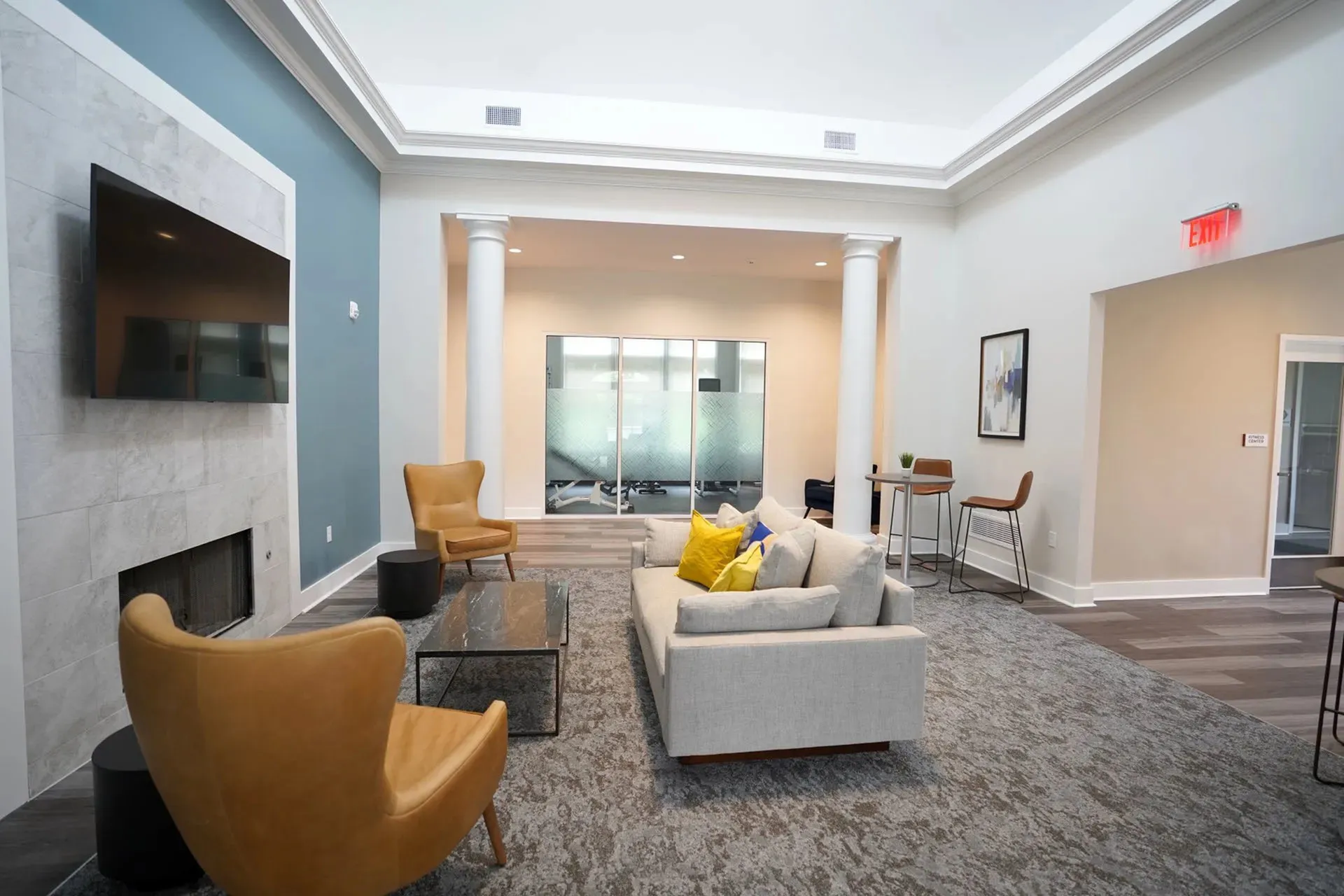 Elegant lounge area with modern decor, featuring cozy seating, a large TV, and stylish accents under a bright, lofty ceiling.