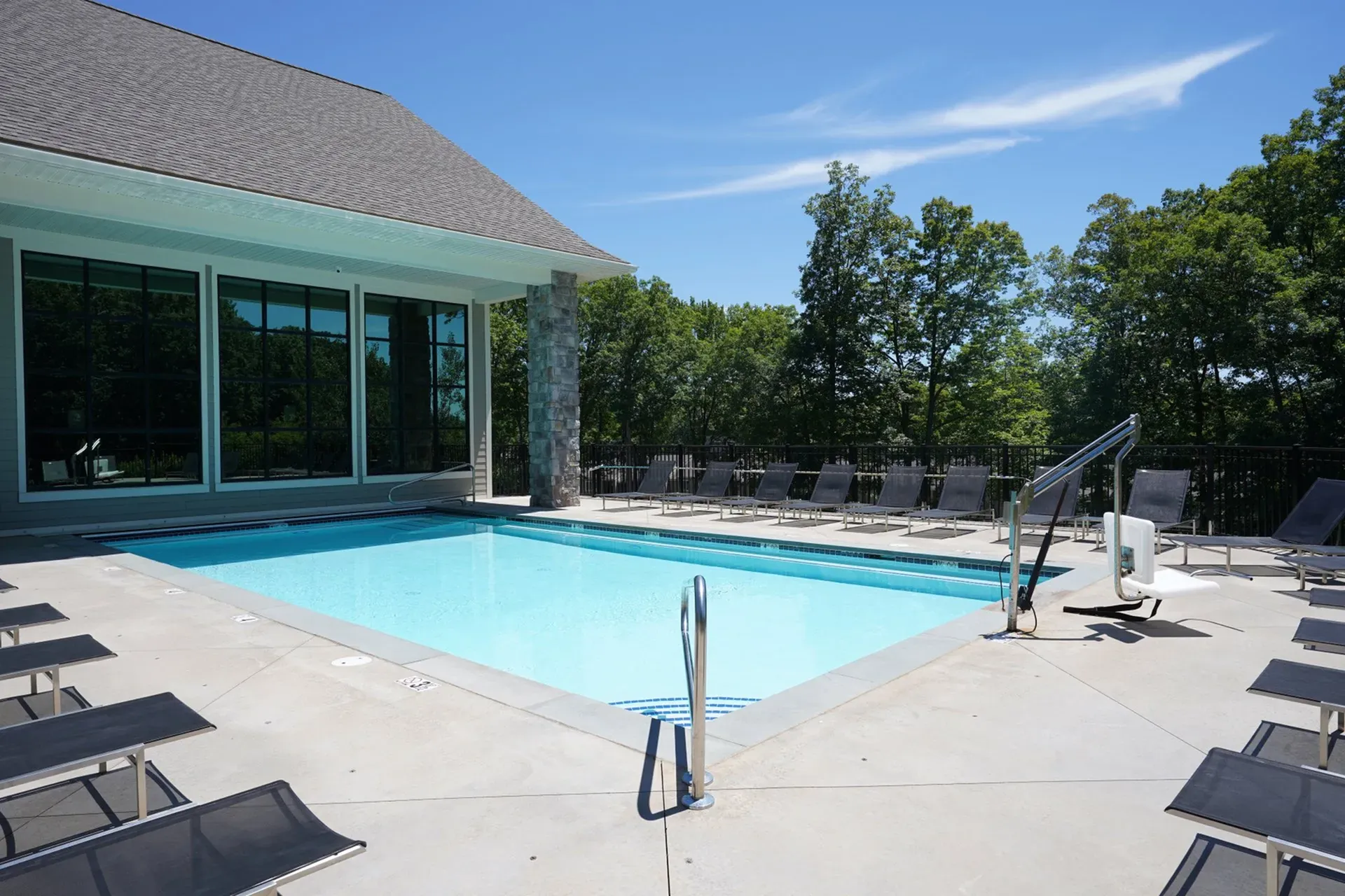 Inviting outdoor pool area with sleek lounge chairs, surrounded by lush greenery and modern architecture.
