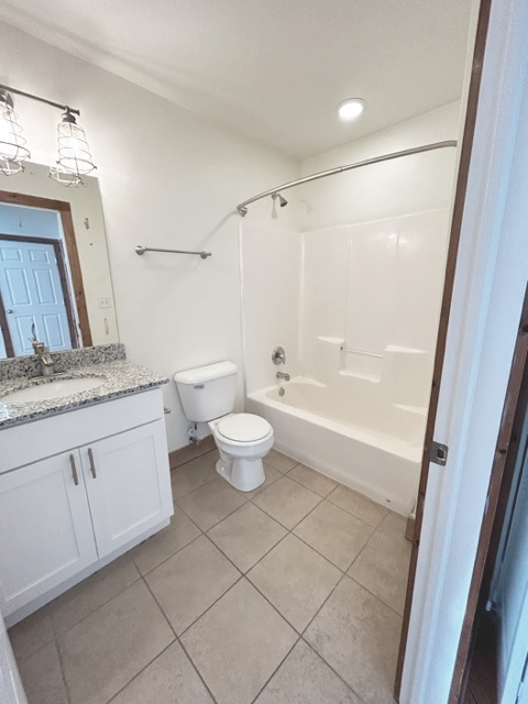 Modern bathroom with elegant granite countertop, sleek white cabinetry, and a pristine bathtub in a contemporary apartment.