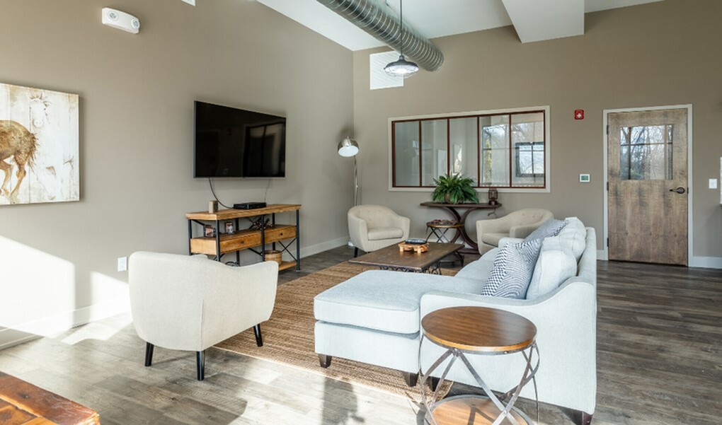 Modern living room with cozy seating, stylish decor, and natural light streaming through large windows.