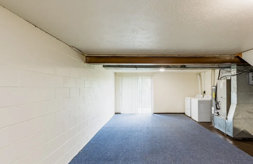 Spacious basement with bright natural light, featuring modern laundry appliances and sleek white walls, ideal for multi-functional use.