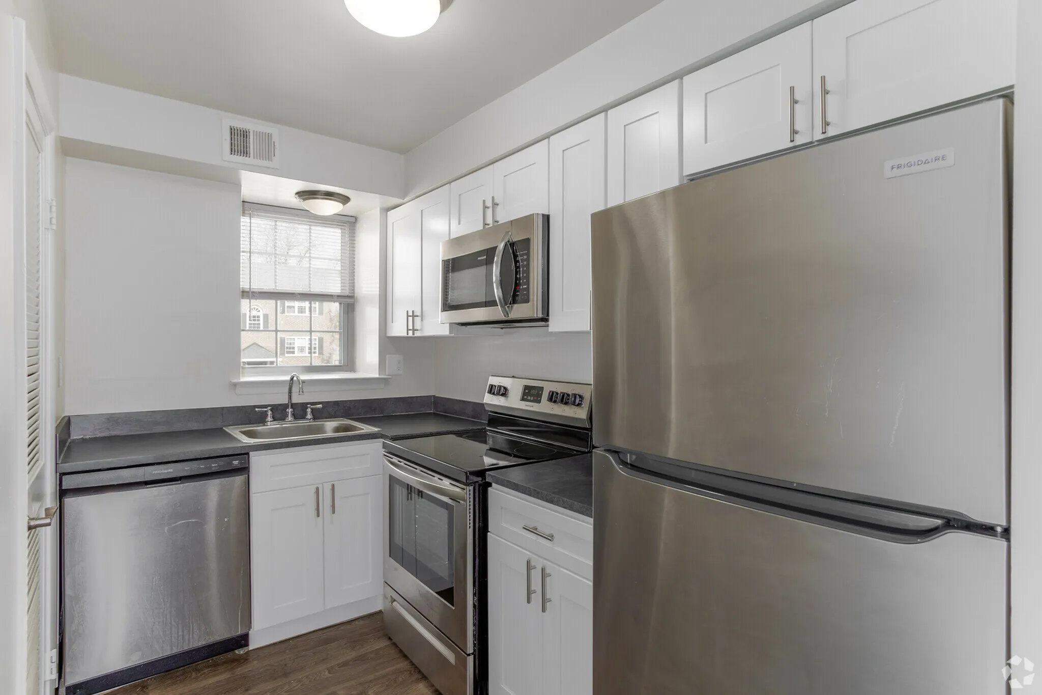 Modern kitchen with sleek stainless steel appliances, white cabinetry, and a sunlit window for a bright and inviting atmosphere.