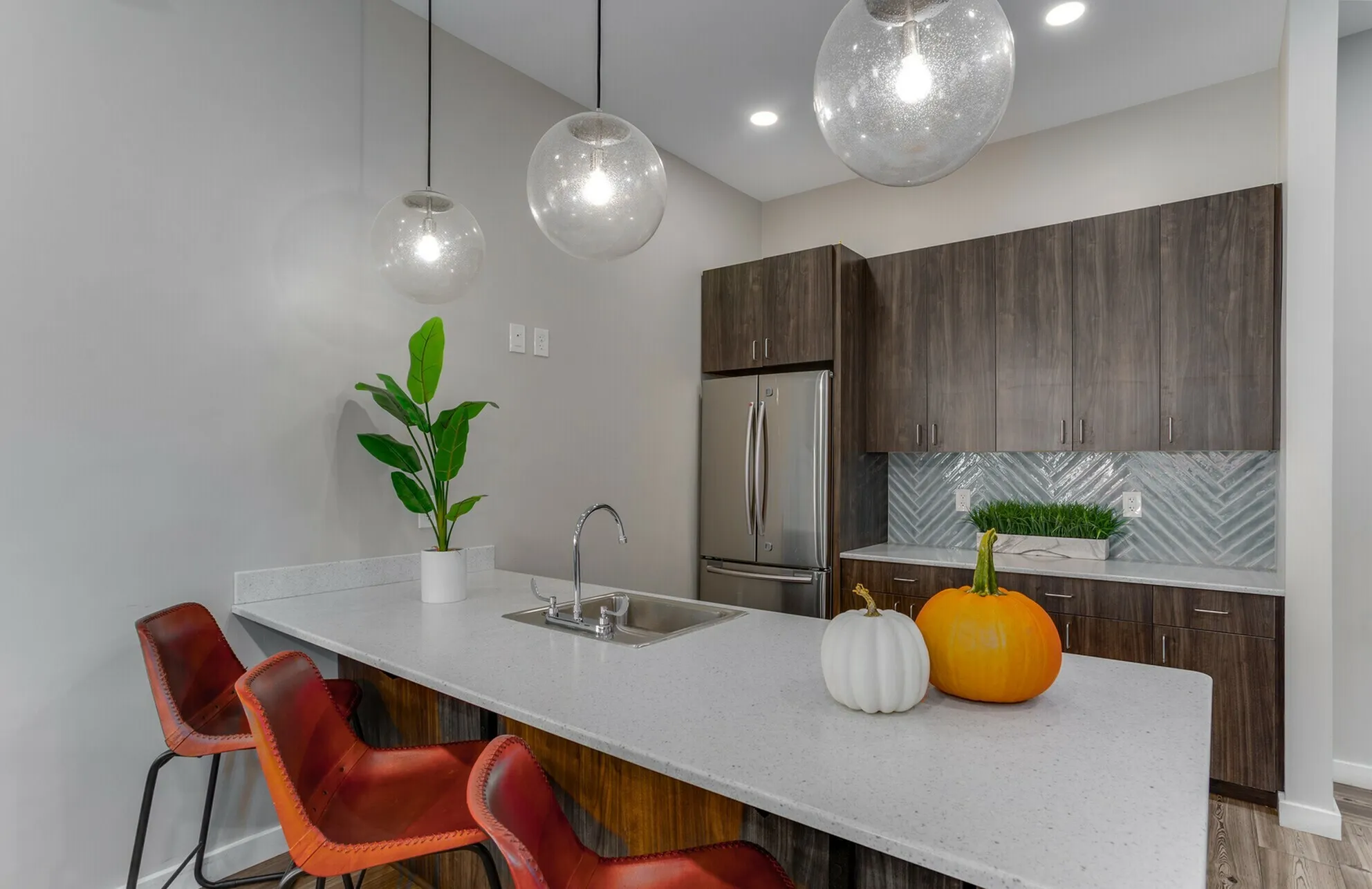 Modern kitchen with elegant pendant lighting, sleek countertops, stainless steel appliances, and stylish bar stools.