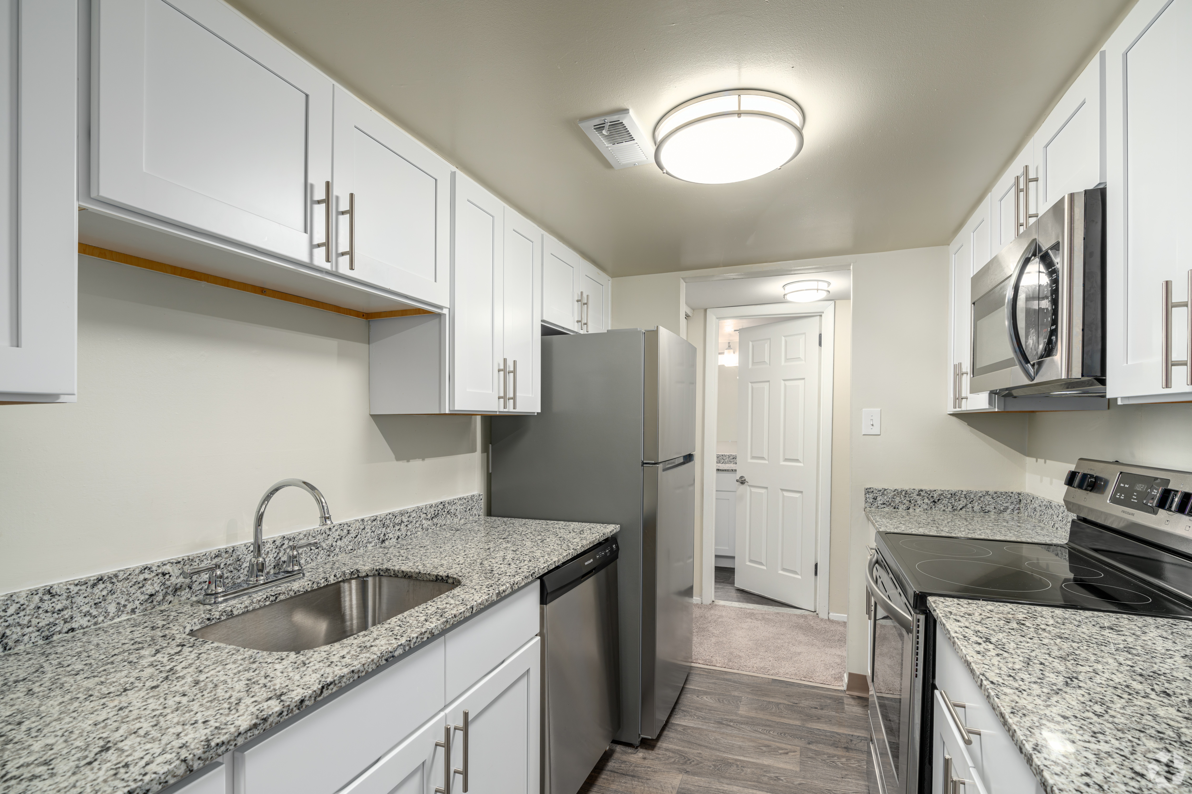 Modern kitchen with sleek stainless steel appliances, granite countertops, and stylish white cabinetry.