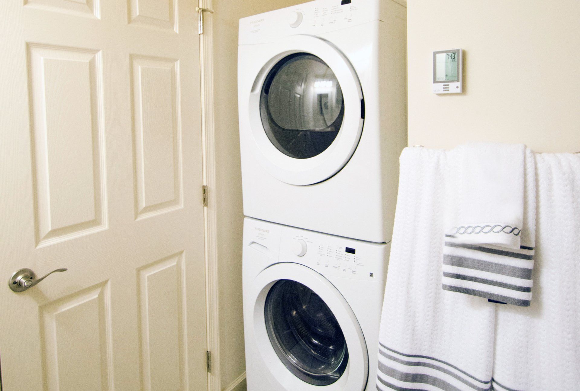 Modern laundry nook with sleek stackable washer and dryer, complemented by fresh white and grey towels for an inviting touch.