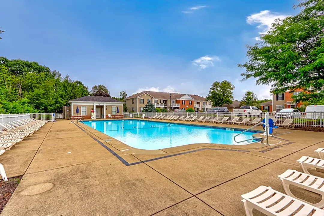 Inviting apartment community with sparkling outdoor pool, surrounded by comfortable lounge chairs and lush greenery.