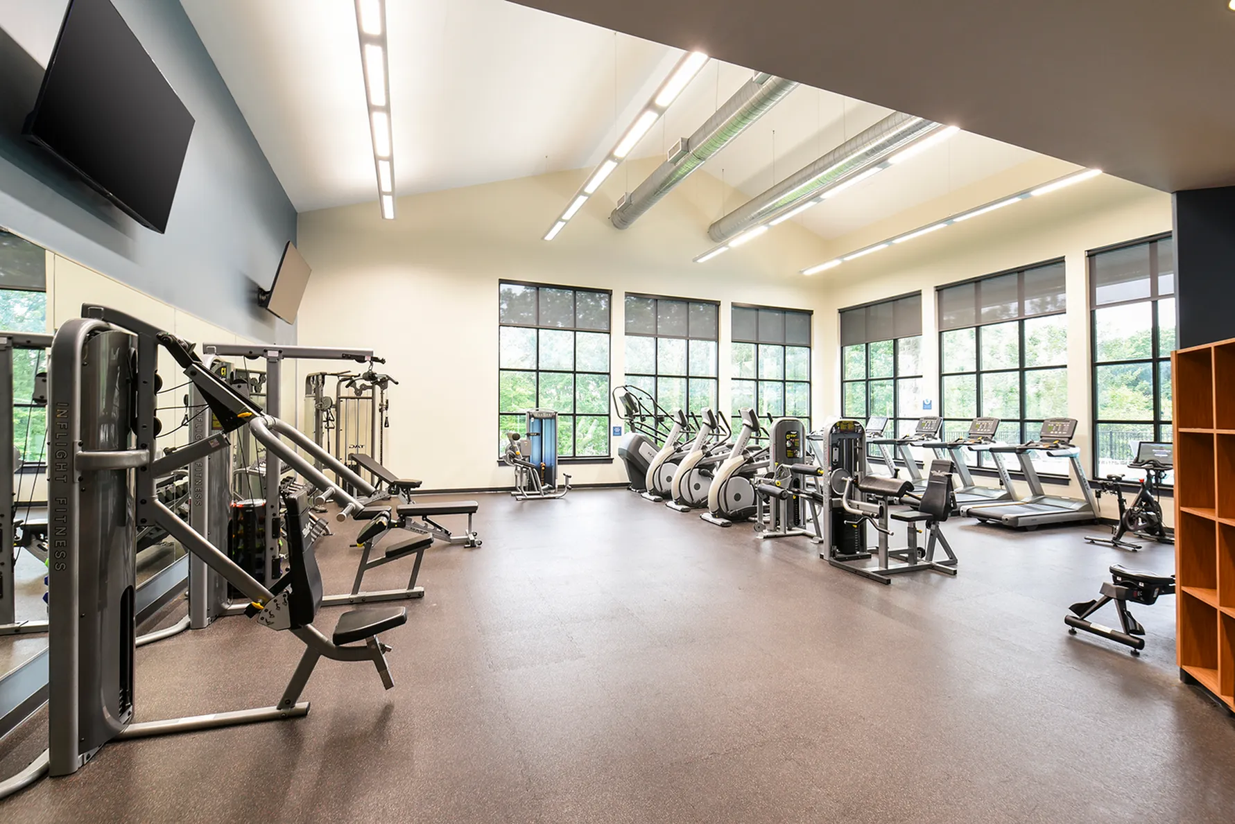 Spacious and modern gym with state-of-the-art fitness equipment, large windows, and bright lighting.
