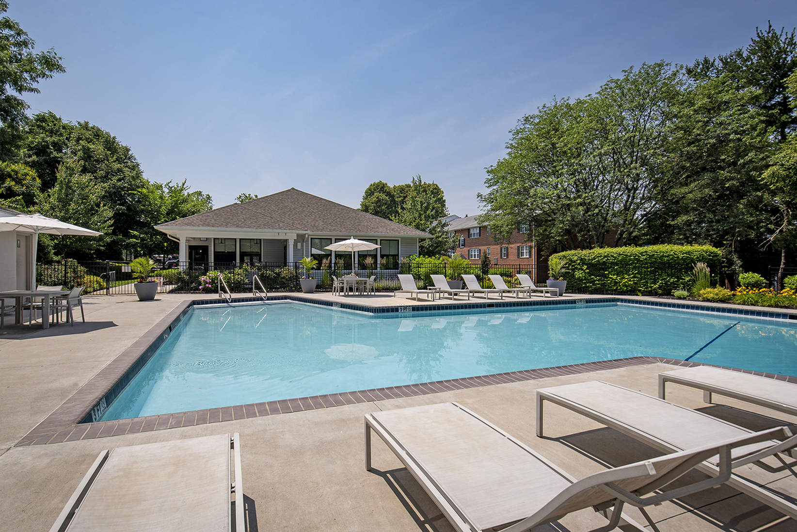 Inviting outdoor swimming pool surrounded by elegant lounge chairs and vibrant greenery, perfect for a relaxing retreat.