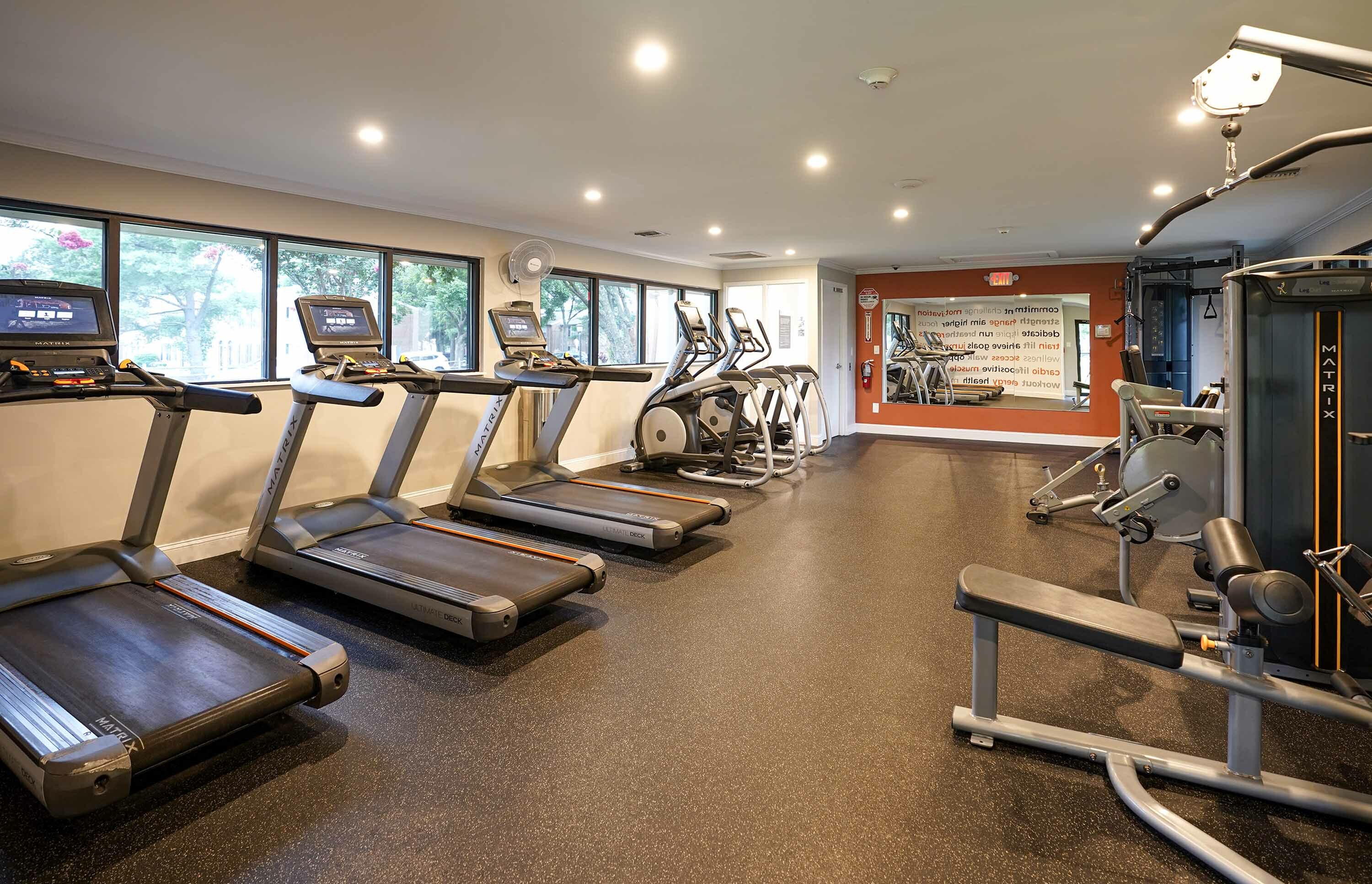 Modern fitness center with state-of-the-art treadmills, exercise bikes, and strength training equipment, offering a bright and inviting workout space.