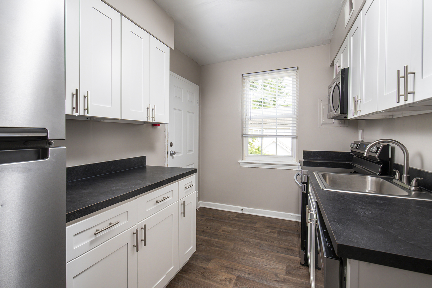 Sleek modern kitchen with white cabinets, stainless steel appliances, and elegant black countertops.