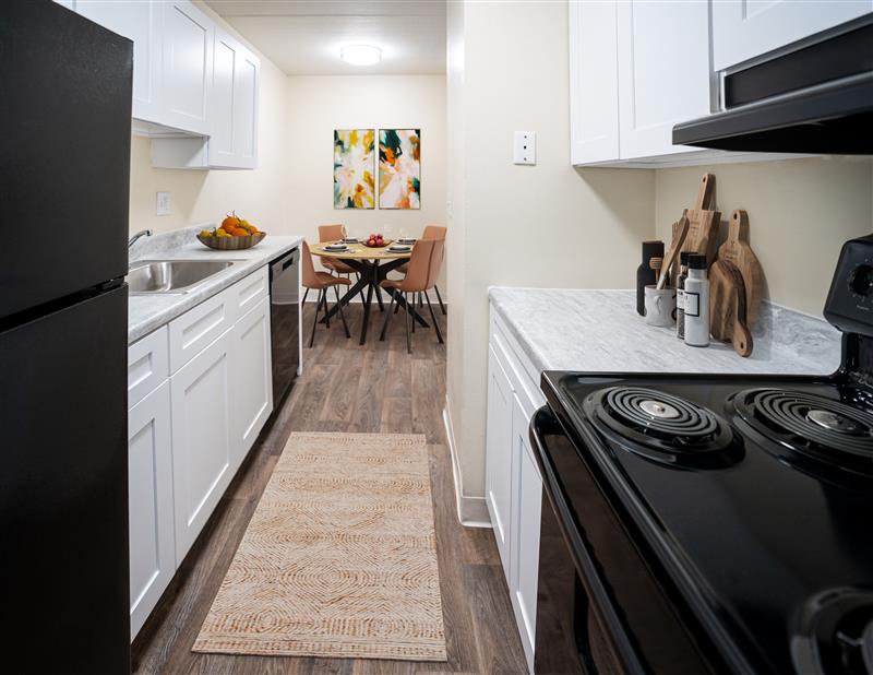 Modern kitchen with sleek white cabinetry, elegant marble countertops, and an adjacent dining area featuring stylish artwork.