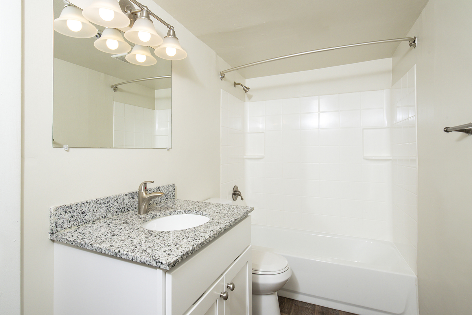 Sleek modern bathroom with elegant lighting, granite countertop, and pristine tiled shower.