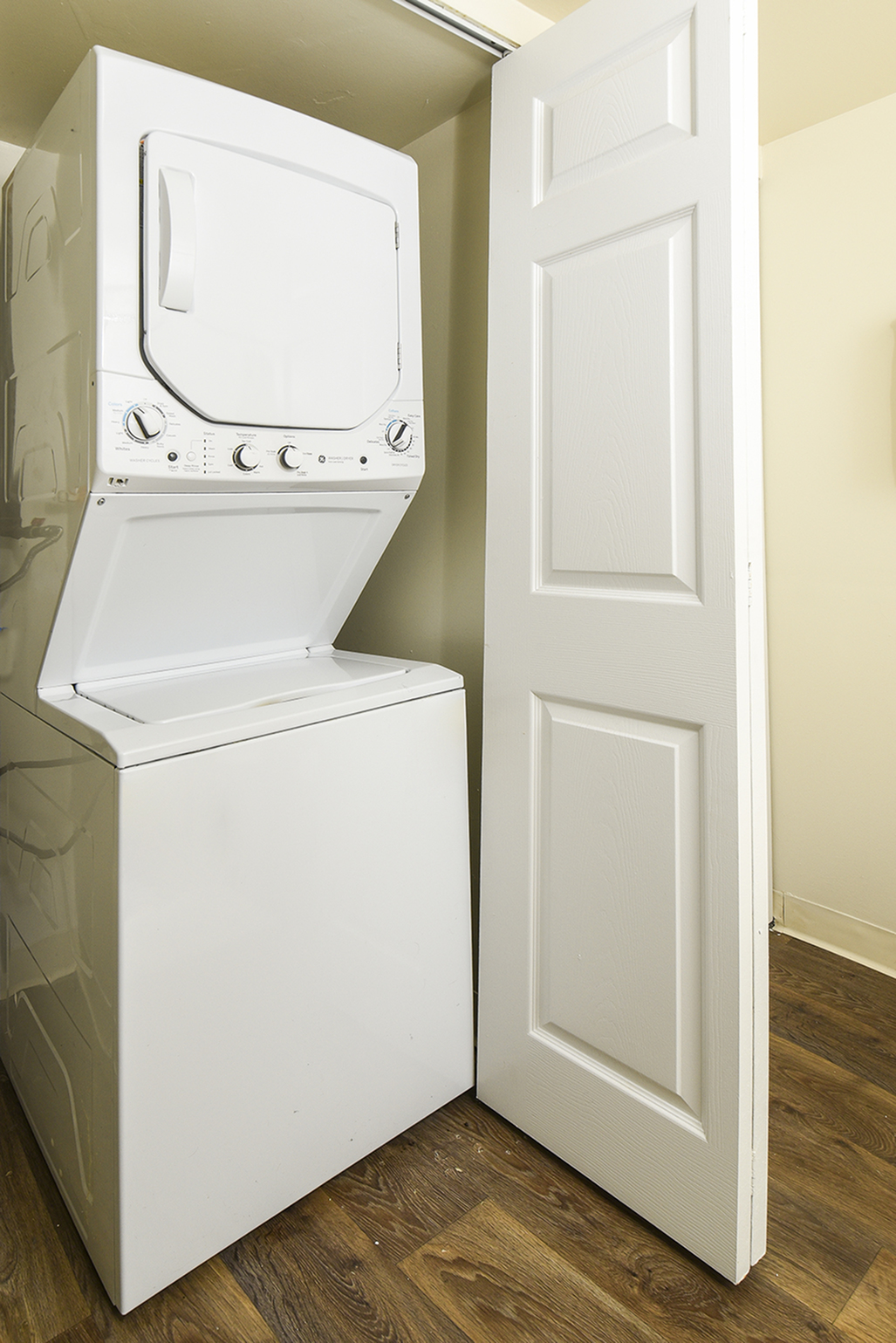 Convenient in-unit laundry area featuring a sleek stacked washer and dryer set against a warm-toned wall, perfect for modern living.