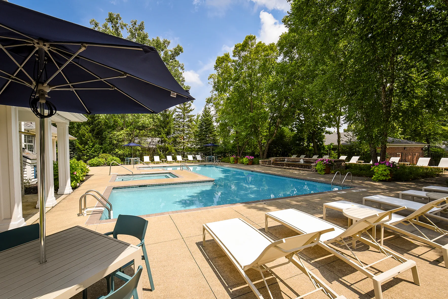 Tranquil outdoor pool area with elegant loungers and lush greenery, perfect for relaxation and leisure.