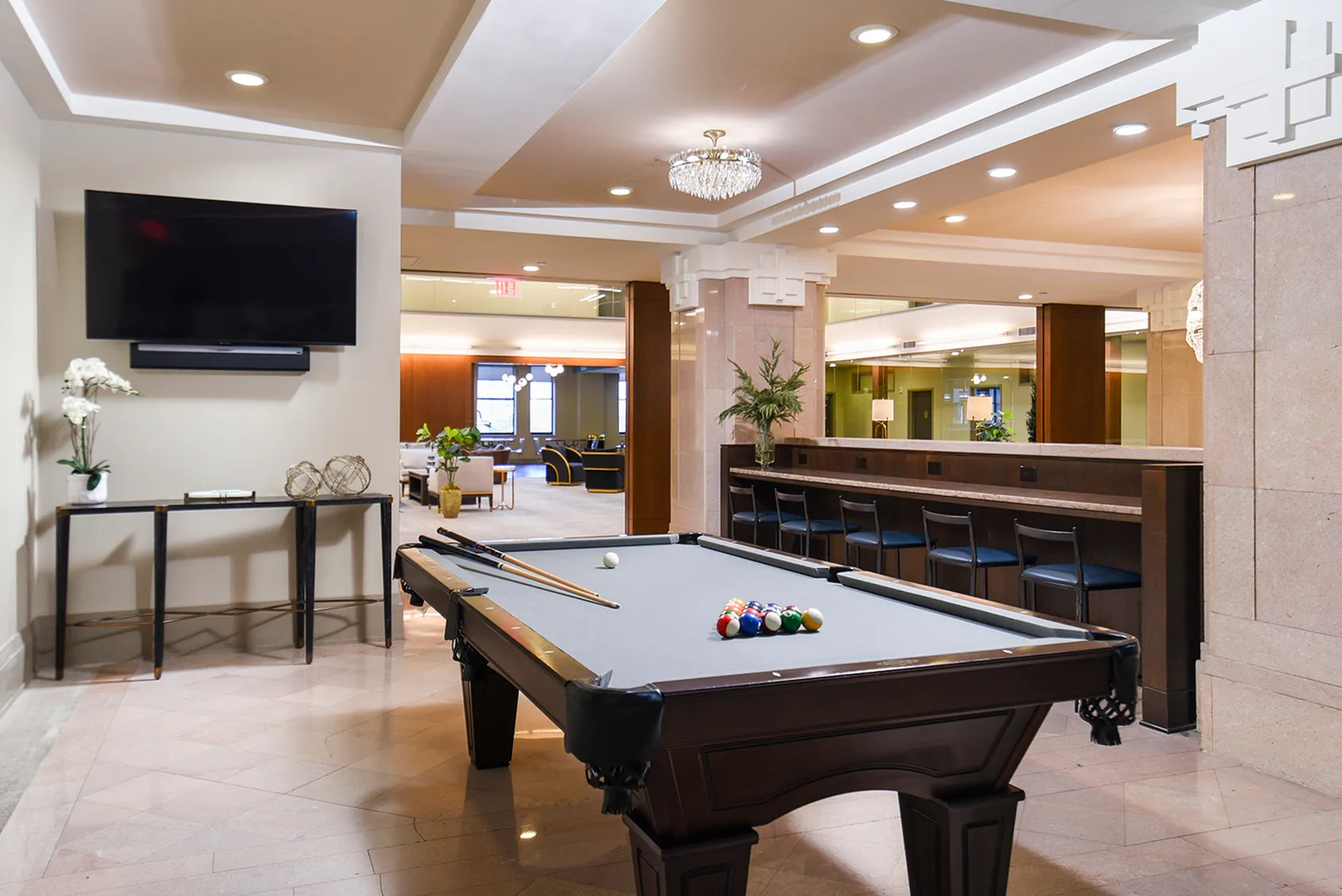 Elegant recreation area featuring a stylish billiards table, modern bar seating, and a luxurious setting for entertainment and relaxation.