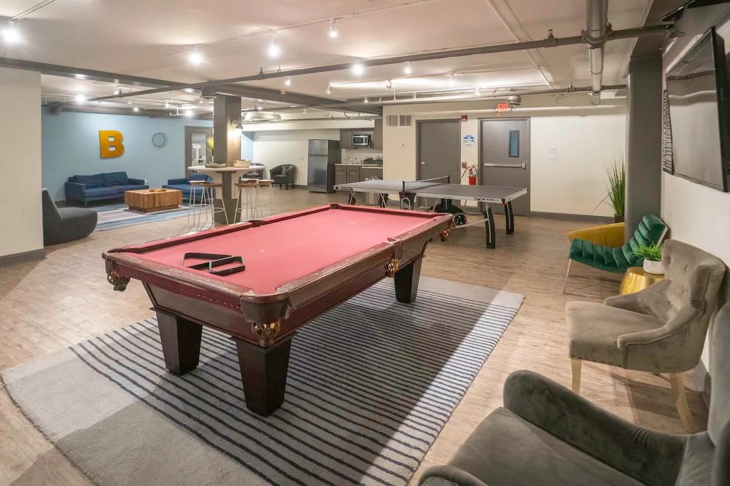 Vibrant recreation room boasting a classic red pool table, a ping pong setup, cozy seating, and ambient lighting for ultimate relaxation.