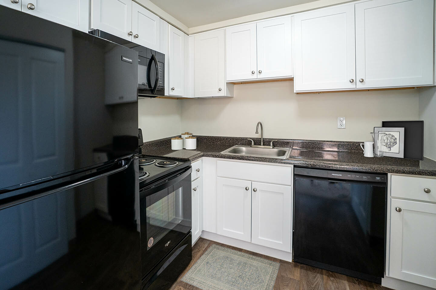 Modern kitchen with sleek black appliances, elegant white cabinets, and a polished granite countertop.