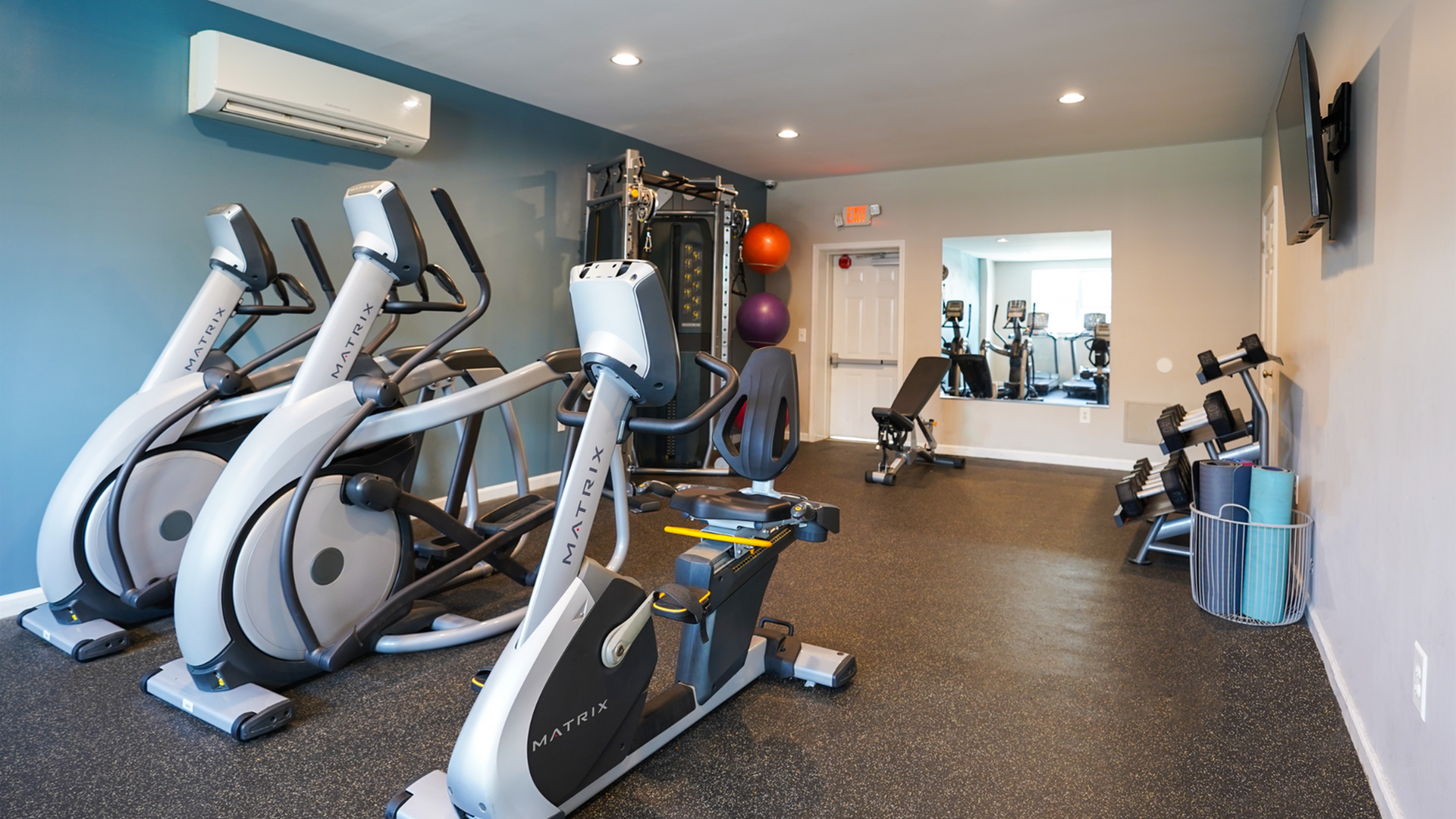 Modern fitness center with state-of-the-art exercise machines, free weights, and yoga mats in a bright, inviting space.