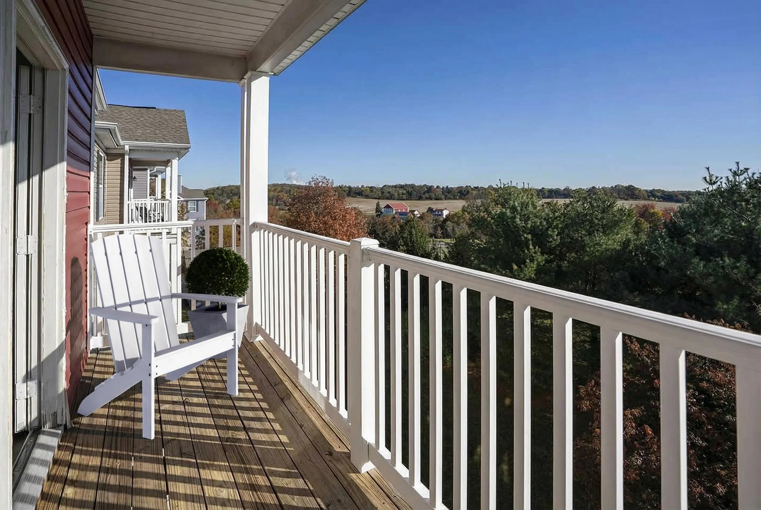 Charming balcony with a scenic view of lush greenery, featuring a cozy white chair and a potted plant, perfect for relaxation.