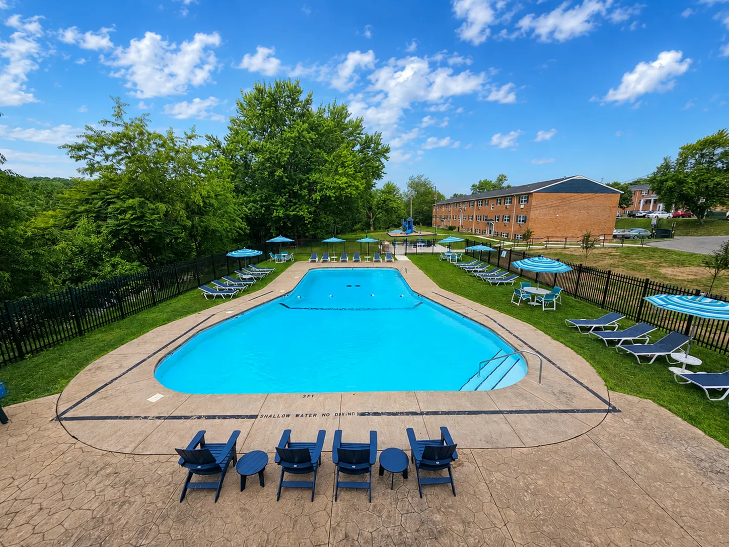 Inviting outdoor pool area with sun loungers, umbrellas, and lush greenery, perfect for relaxation and leisure.