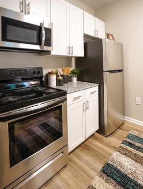 kitchen with white cabinets, granite countertops and stainless steel range, microwave and refrigerator