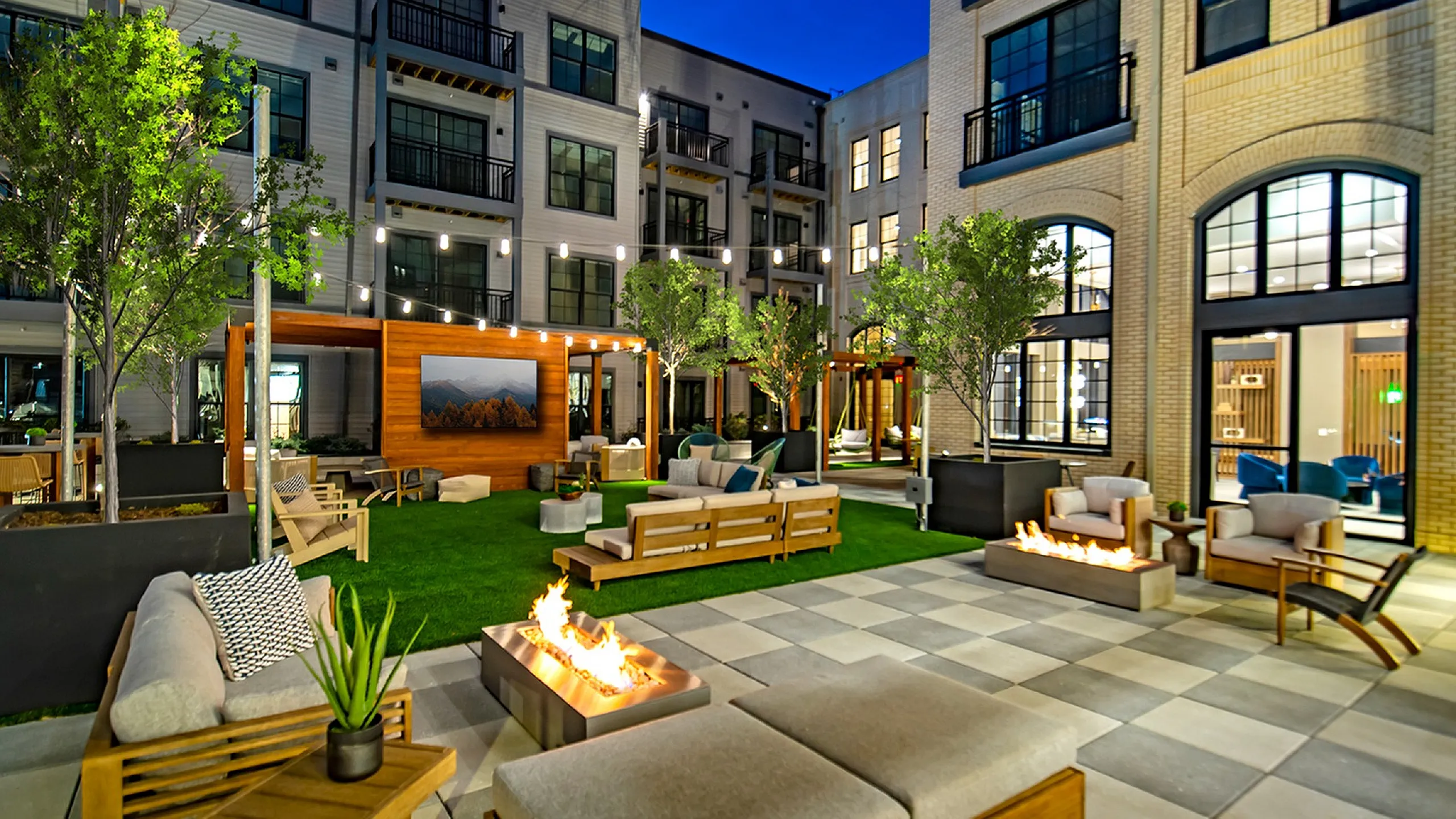 Luxurious apartment courtyard featuring cozy seating, ambient lighting, and stylish fire pits.