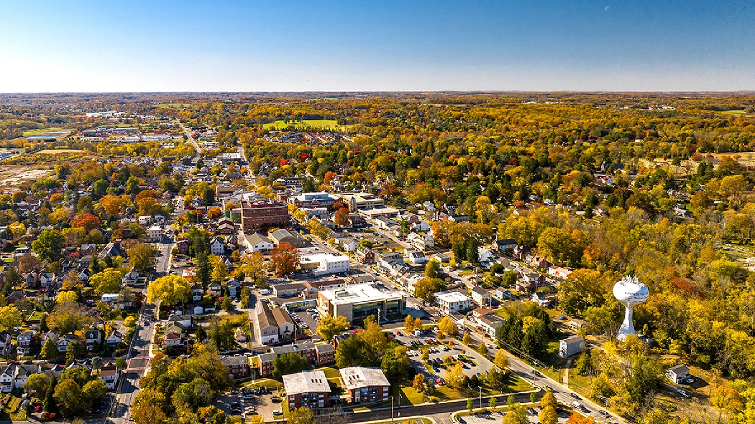 Aerial view of a vibrant suburban neighborhood with lush greenery and colorful autumn foliage.
