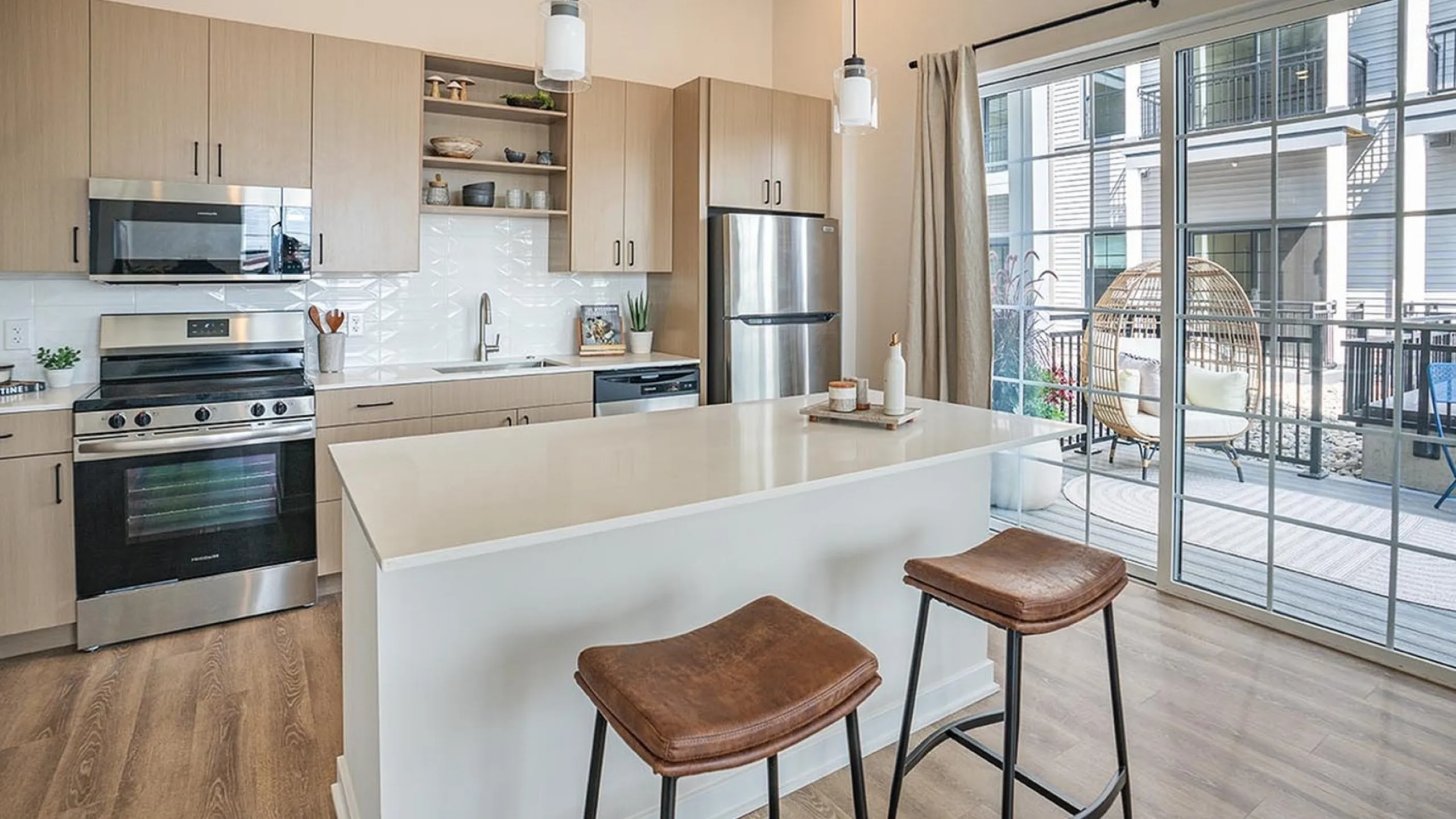 Bright modern kitchen with sleek cabinetry, center island, and outdoor view.