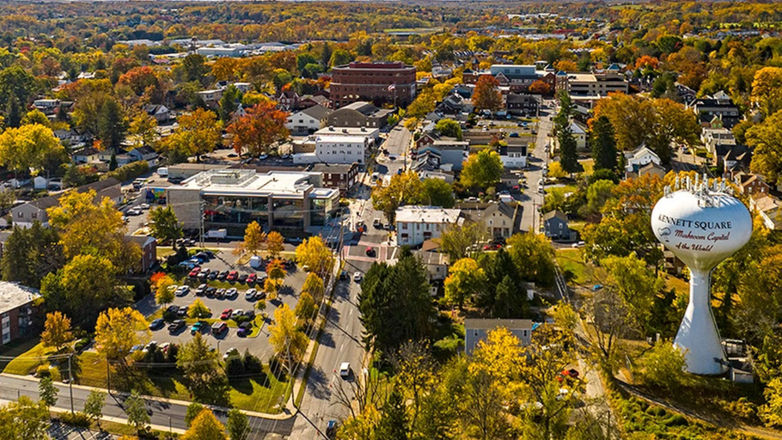 Aerial view of a picturesque town surrounded by vibrant foliage and clear skies.