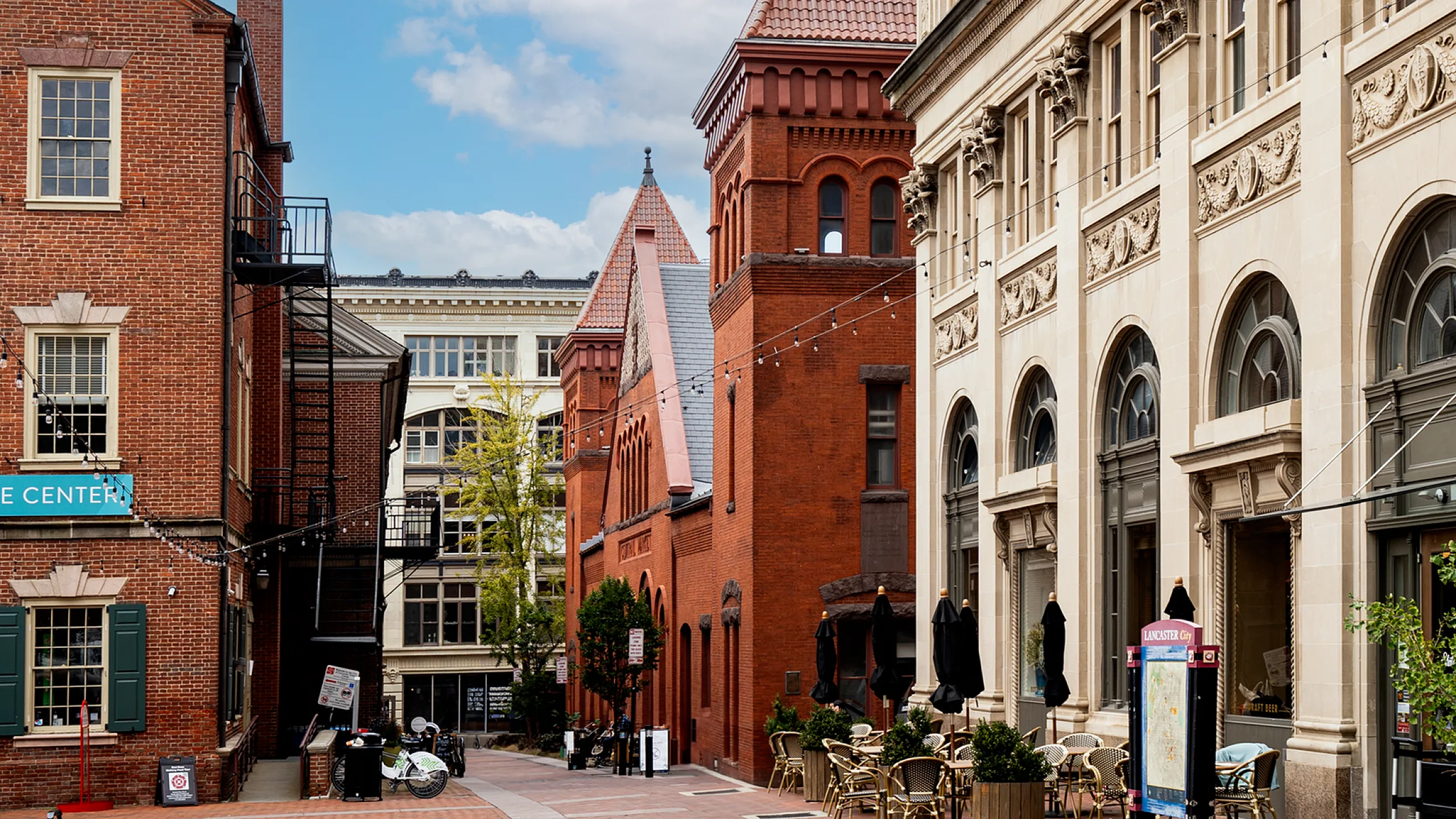 Charming urban street view featuring historic brick buildings and elegant outdoor seating, perfect for city living.