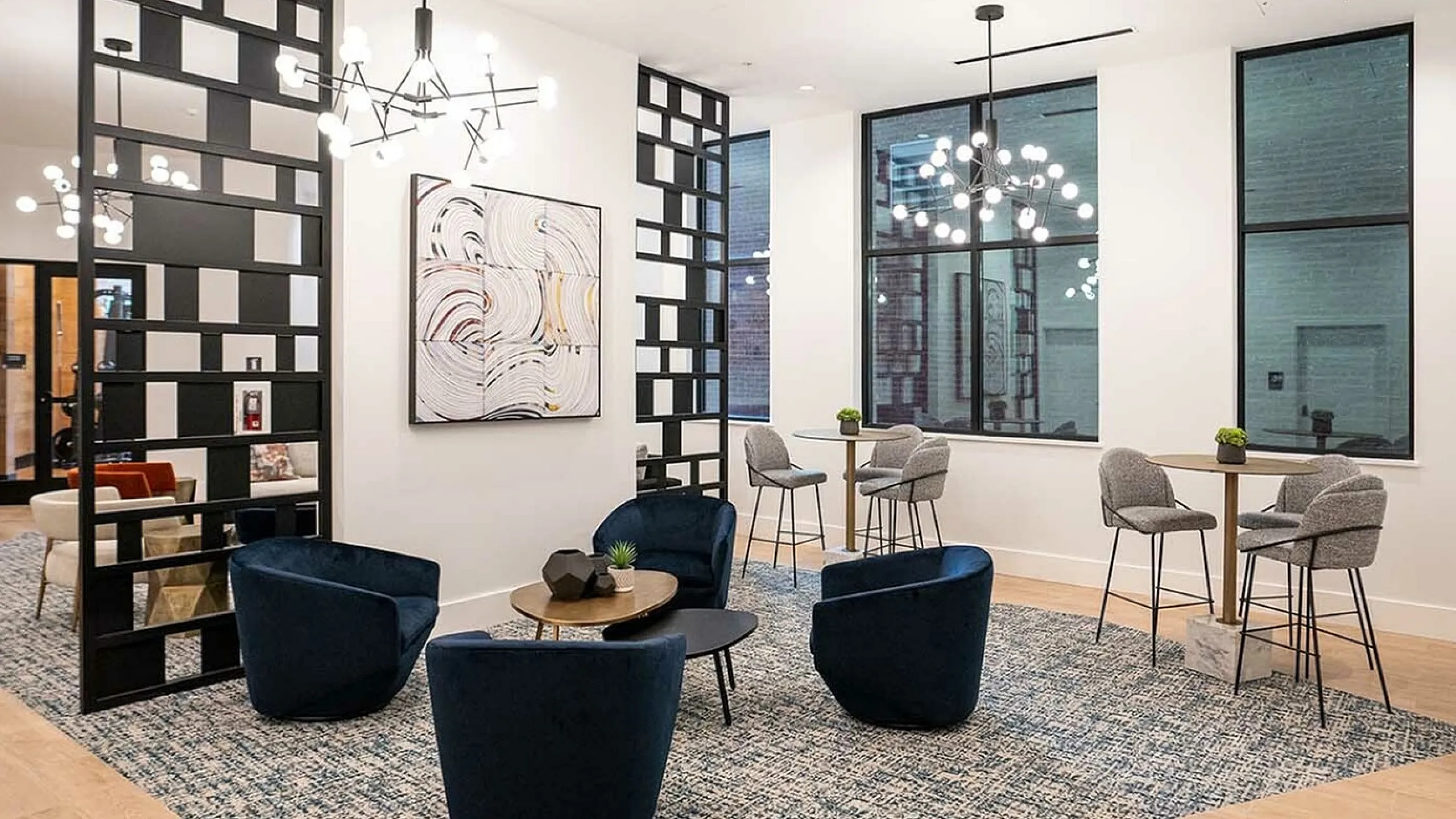 Contemporary seating area with chic blue velvet chairs and stylish lighting in a modern, open lounge space.
