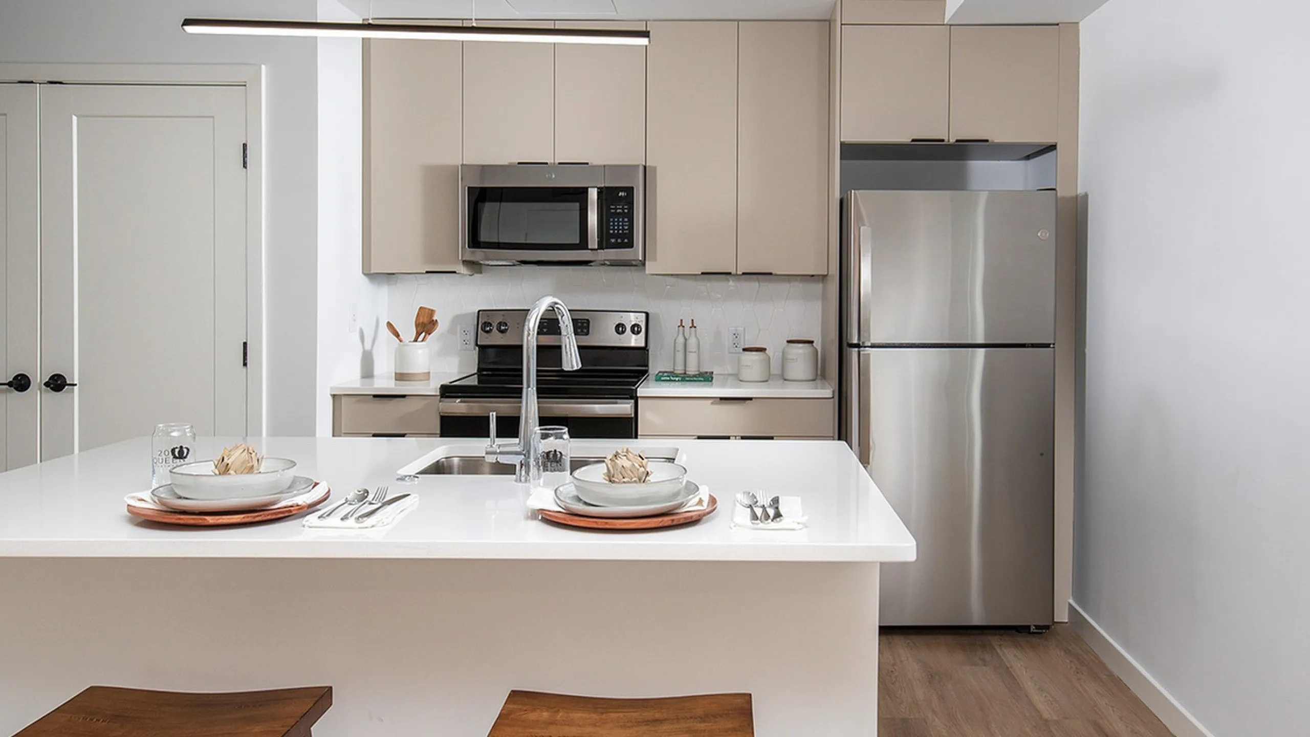 Sleek modern kitchen featuring a stylish island with elegant dining setup, stainless steel appliances, and warm wooden accents.