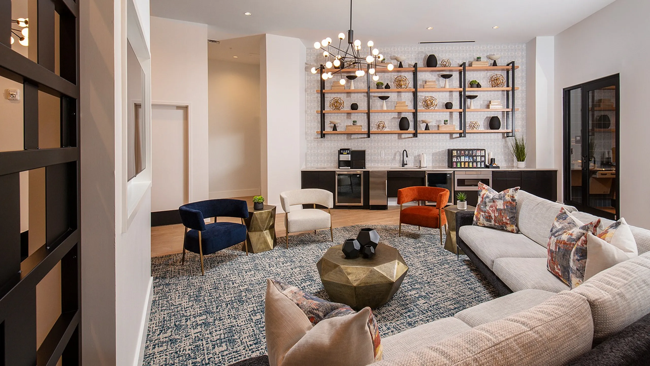 Modern living area with elegant decor, featuring a cozy L-shaped sofa, vibrant accent chairs, stylish bookshelf, and a chic geometric coffee table under contemporary lighting.
