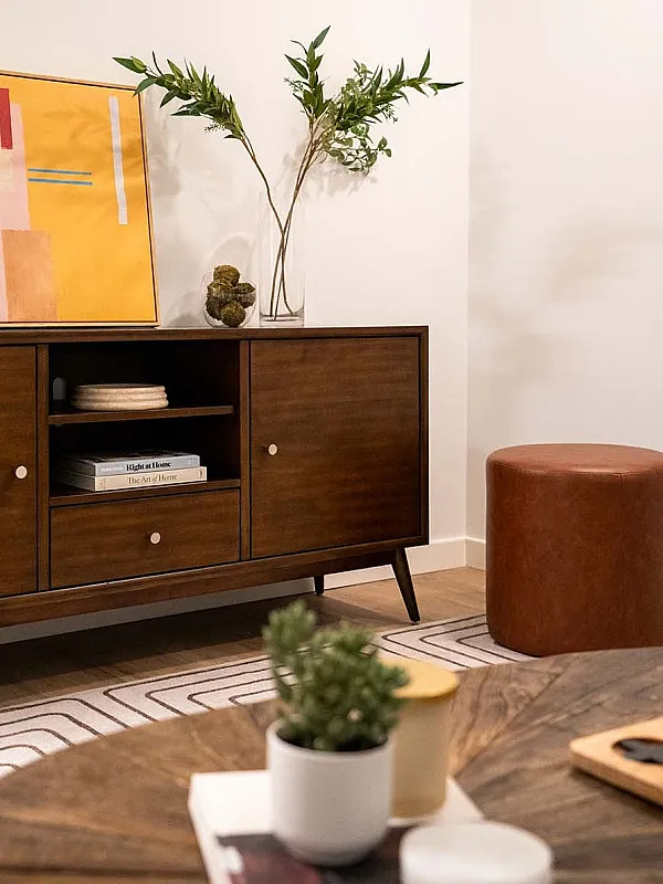 Modern living room corner featuring a chic wooden sideboard, stylish decor, and an elegant plant arrangement.